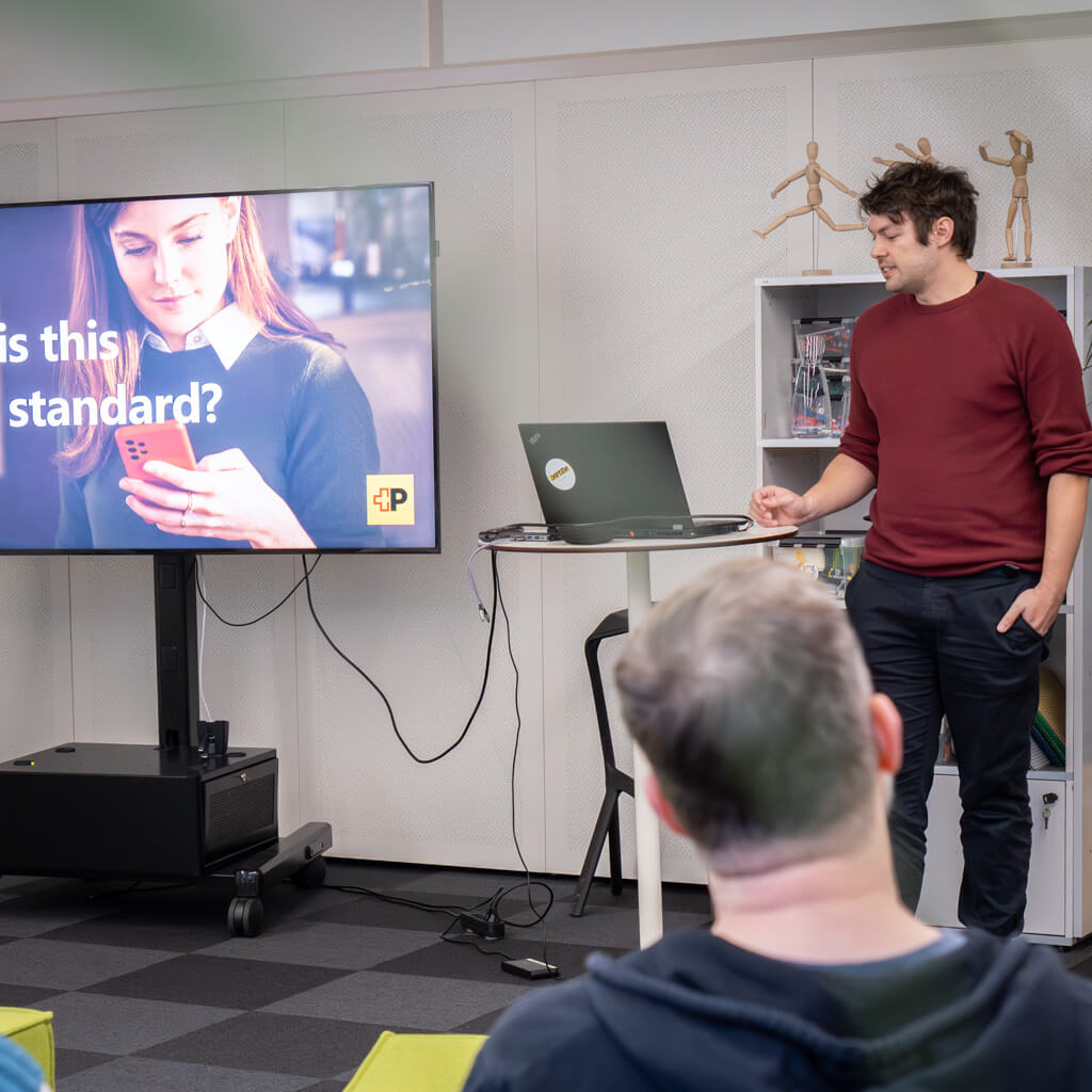 A man in a red sweater presents in an office