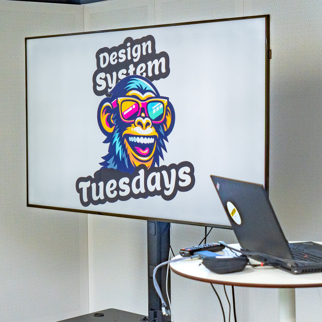 A large screen showing the Design System Tuesdays logo